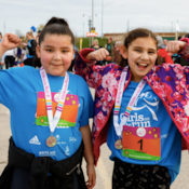 Two Girls on the Run participants flexing their muscles after running the 5K
